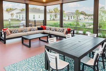 a screened patio with a table and chairs and couches at Anthem Apartments and Luxury Rental Homes in Huntsville, AL